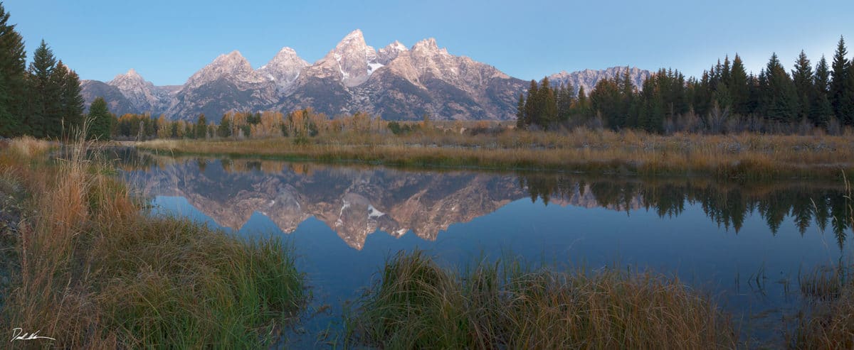 Reflection of Teton mountains at dawn over a small river