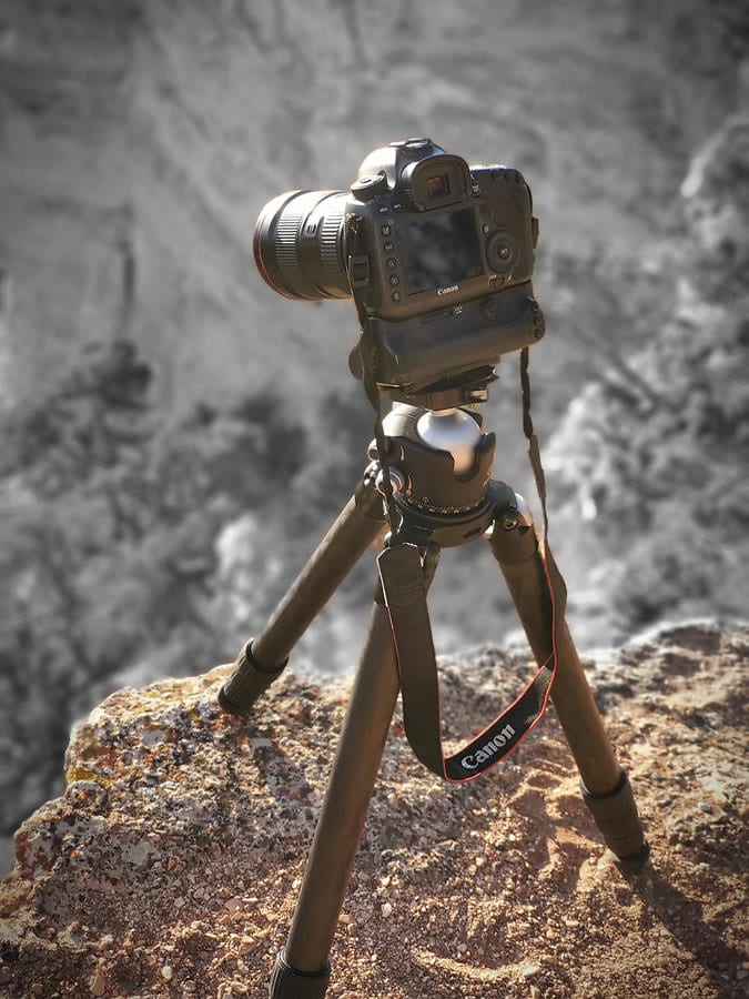 canon camera sitting on tripod at the edge of a canyon