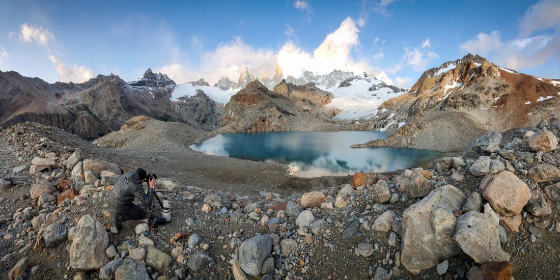 Photograph of Derek Nielsen on a mountain top photographing a lake