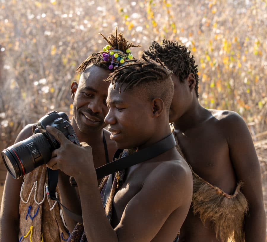 photo of three African tribal men looking at themselves in a canon camera