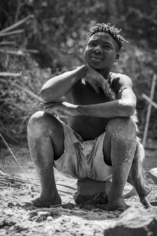 photo of young African tribal member sitting on a stone