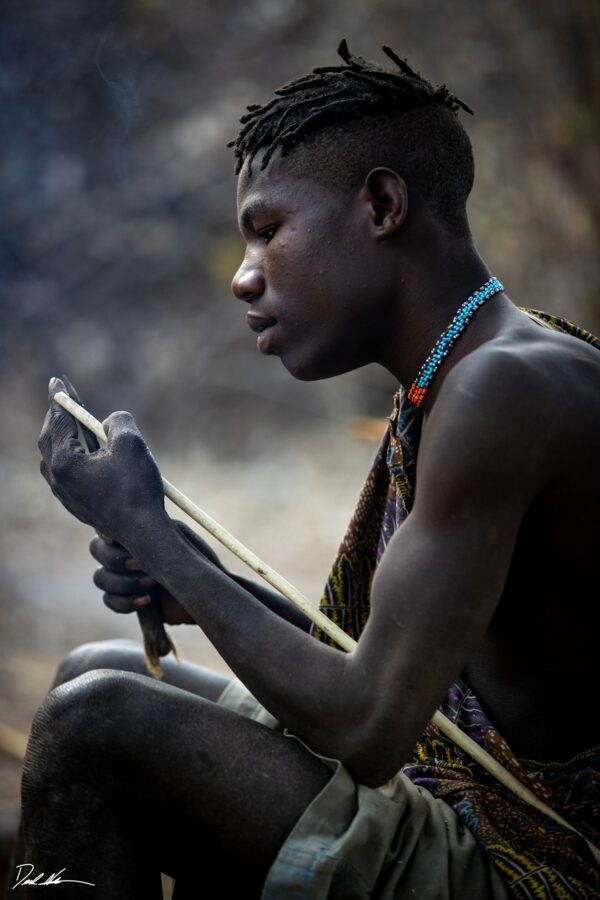 photograph of a young tribal member sharpening his arrow in Tanzania