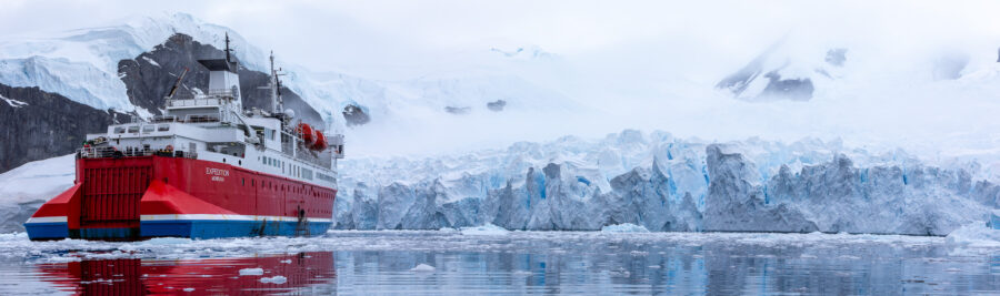 Photograph of the MS Expedition ship in Antarctica facing the mountains and a very large glacier