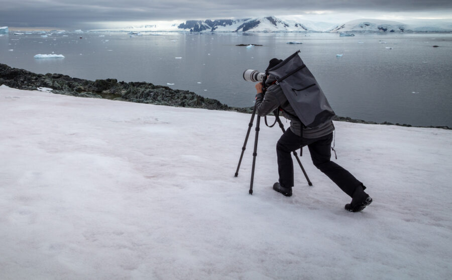 Photo of photographer Derek Nielsen on Antarctica with a tripod and professional camera