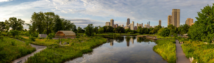 Panoramic image of Lincoln Park in Chicago at sunrise with vibrant green colors and the city skyline in the distance