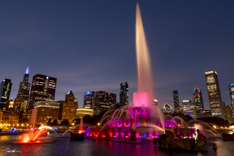 image of Buckingham Fountain in Chicago at sunset with the lights coming on in the city and in the fountain
