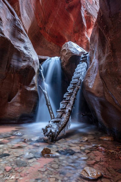 image of a waterfall in a slot canyon in southern Utah with a ladder leading up the way