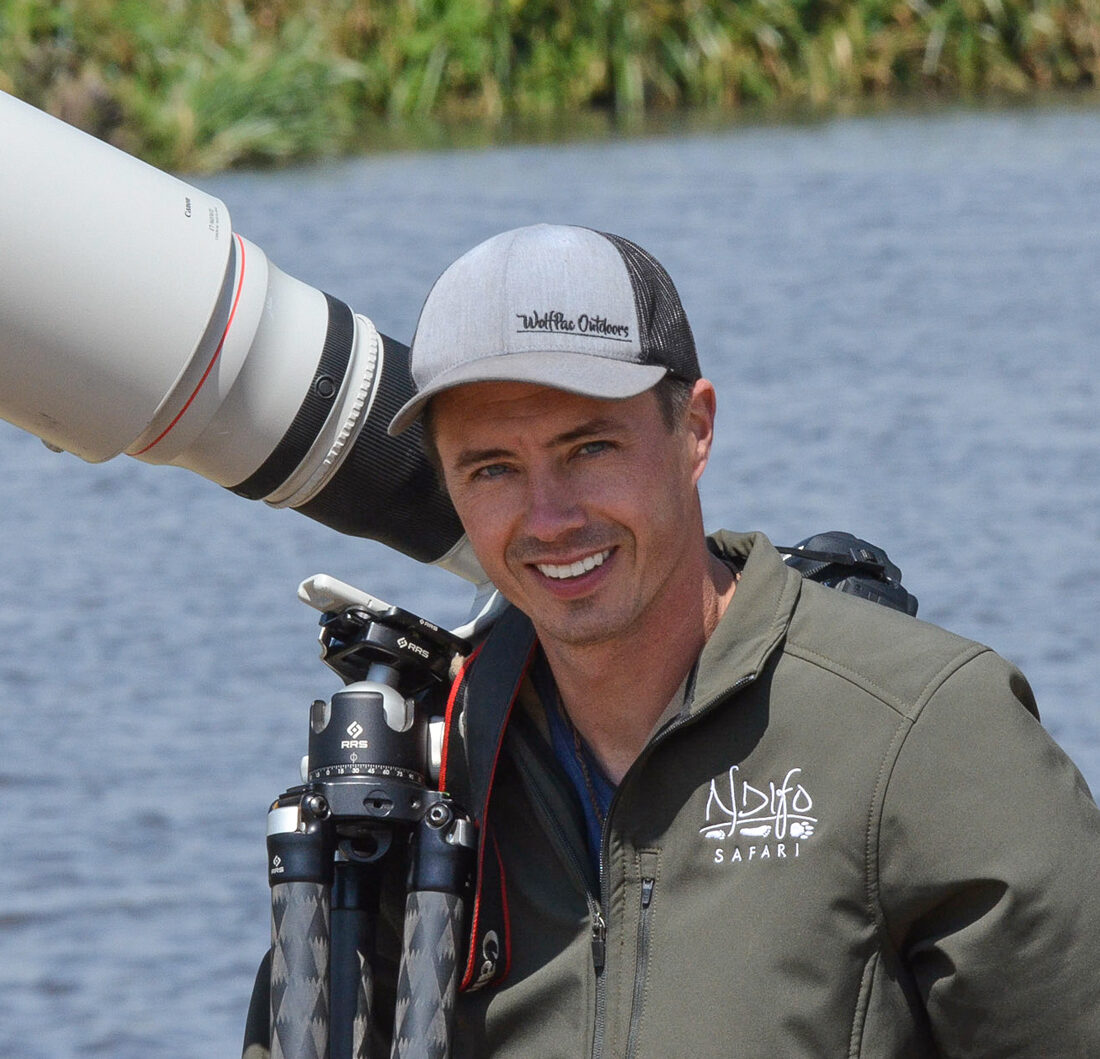 Image of photographer Derek Nielsen holding a 600mm lens while out photographing wildlife in Africa