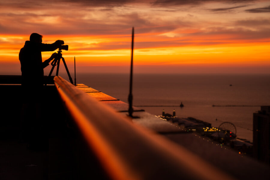 Image of photographer Derek Nielsen on top of a skyscraper in Chicago during sunrise doing photography