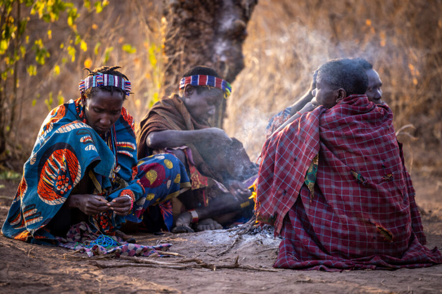 Hadzabe women making beaded jewelry around a fire