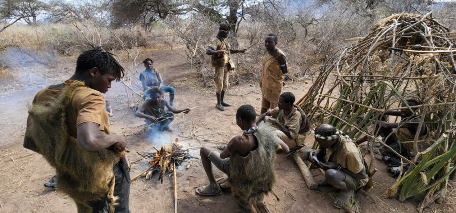 group of hadzabe tribal members sitting around the fire in the morning