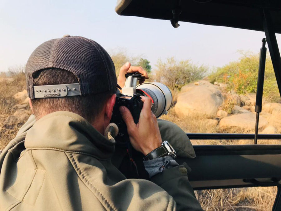 professional wildlife photographer Derek Nielsen in the Serengetti National Park photographing a leopard from a jeep