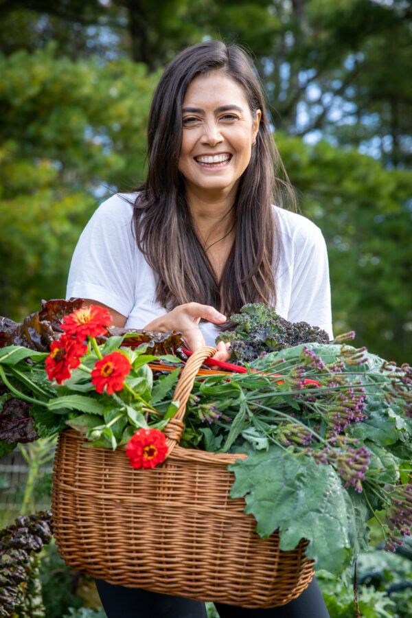 attractive woman holding a basket of fresh flowers and vegetables