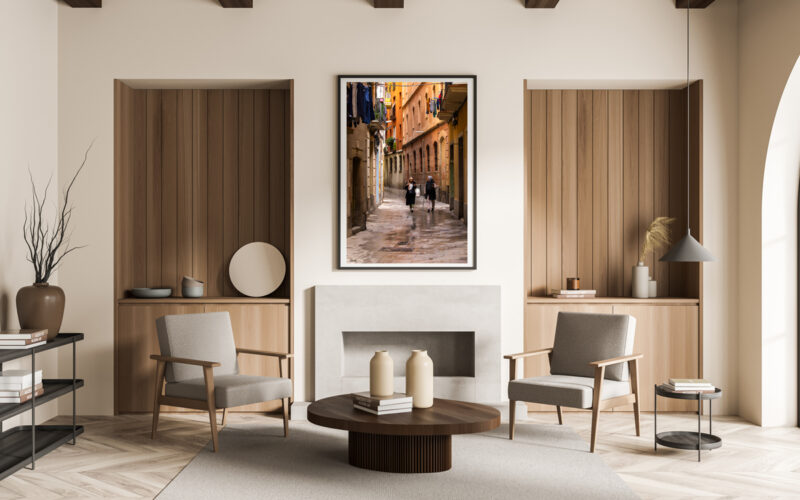 Large framed fine art print of two women walking down a narrow street in Barcelona displayed in the living room of a modern home