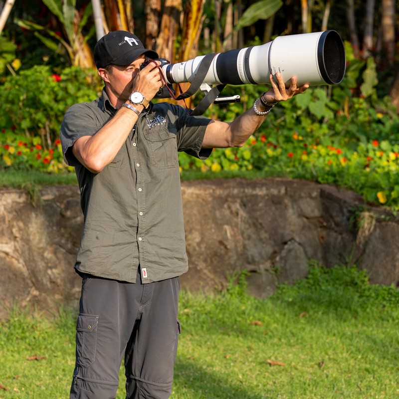Professional photographer Derek Nielsen using a large lens to photograph wildlife in Africa