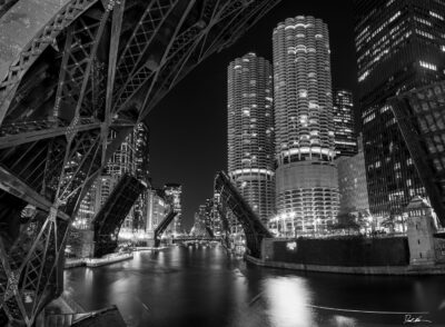 black and white image of the Chicago river with all the bridges up at night