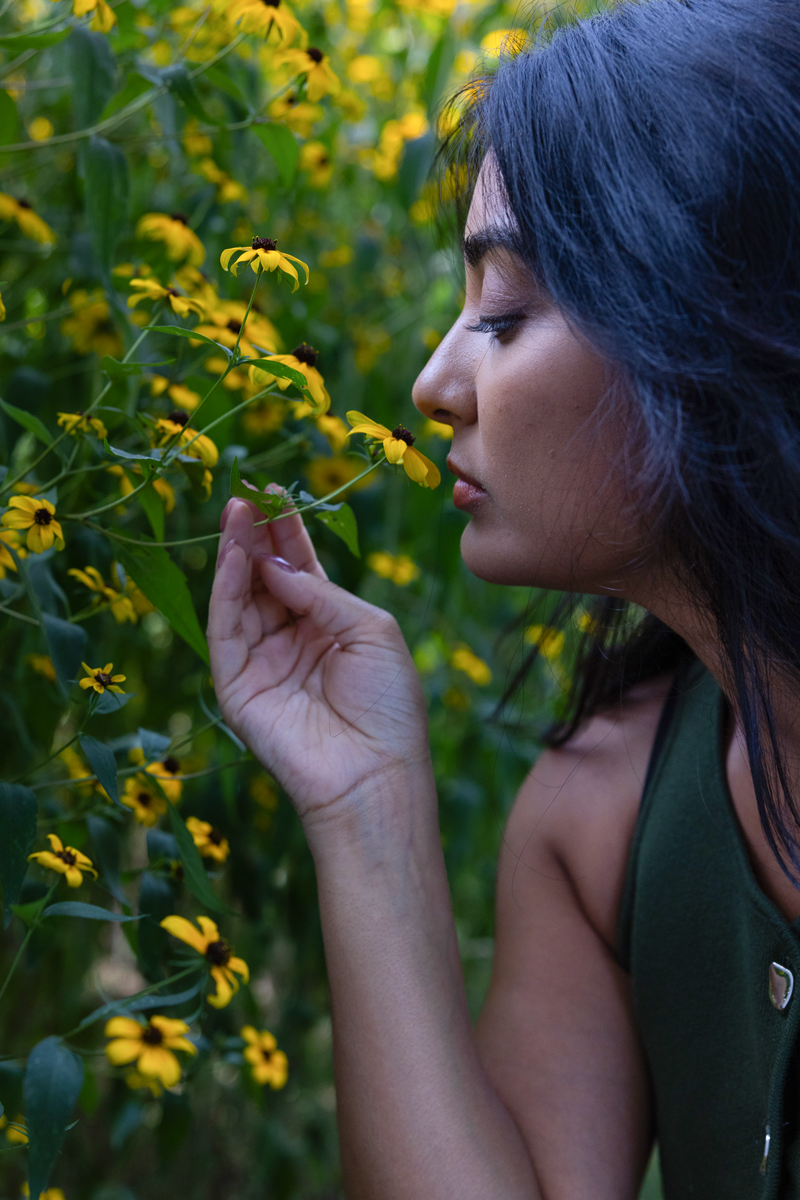 photograph of a beautiful woman smelling a flower