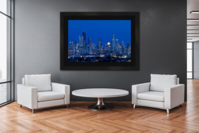 large framed fine art print of the chicago skyline with a moon rising over the city displayed in a downtown office.