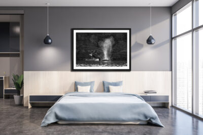 Large framed black and white fine art print of an orca jumping out of the Salish Sea displayed above a bed in a modern condo