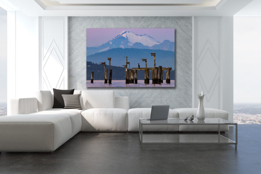 Large unframed fine art print of a mountain over the ocean at sunset displayed in the living room of a modern luxury home