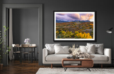 Large framed fine art print of the San Juan Mountains during fall at sunset displayed in the living room of a luxury home