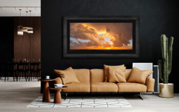 Large framed fine art print of a sunset over the great plains of the United States displayed over a couch in a modern home