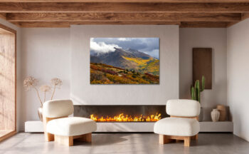 Large unframed fine art print of mountains during fall displayed above the fire place of a modern home