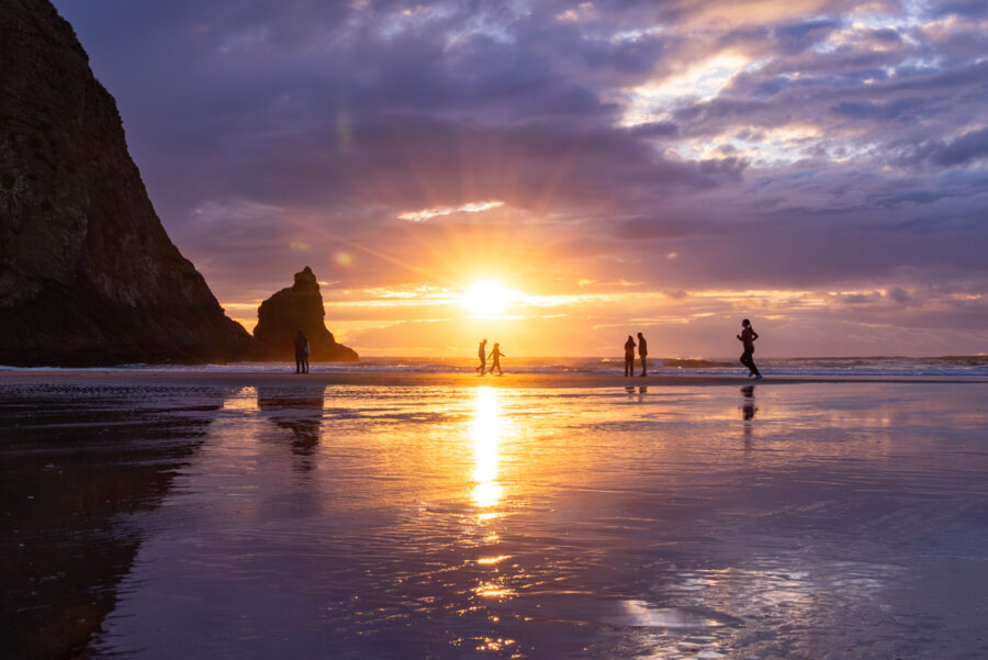 Sunset photography at Cannon Beach in Oregon with people walking on the beach